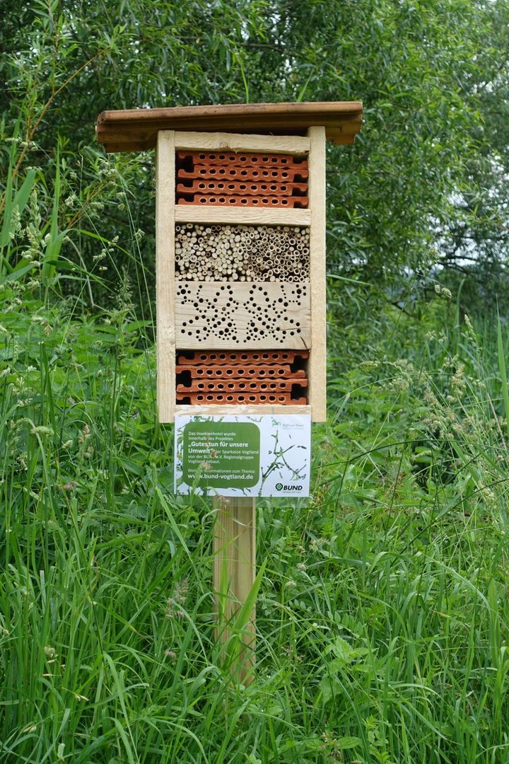 Eine Wildbienen-Nisthilfe mit verschiedenen Nistangeboten steht in einer Wiese