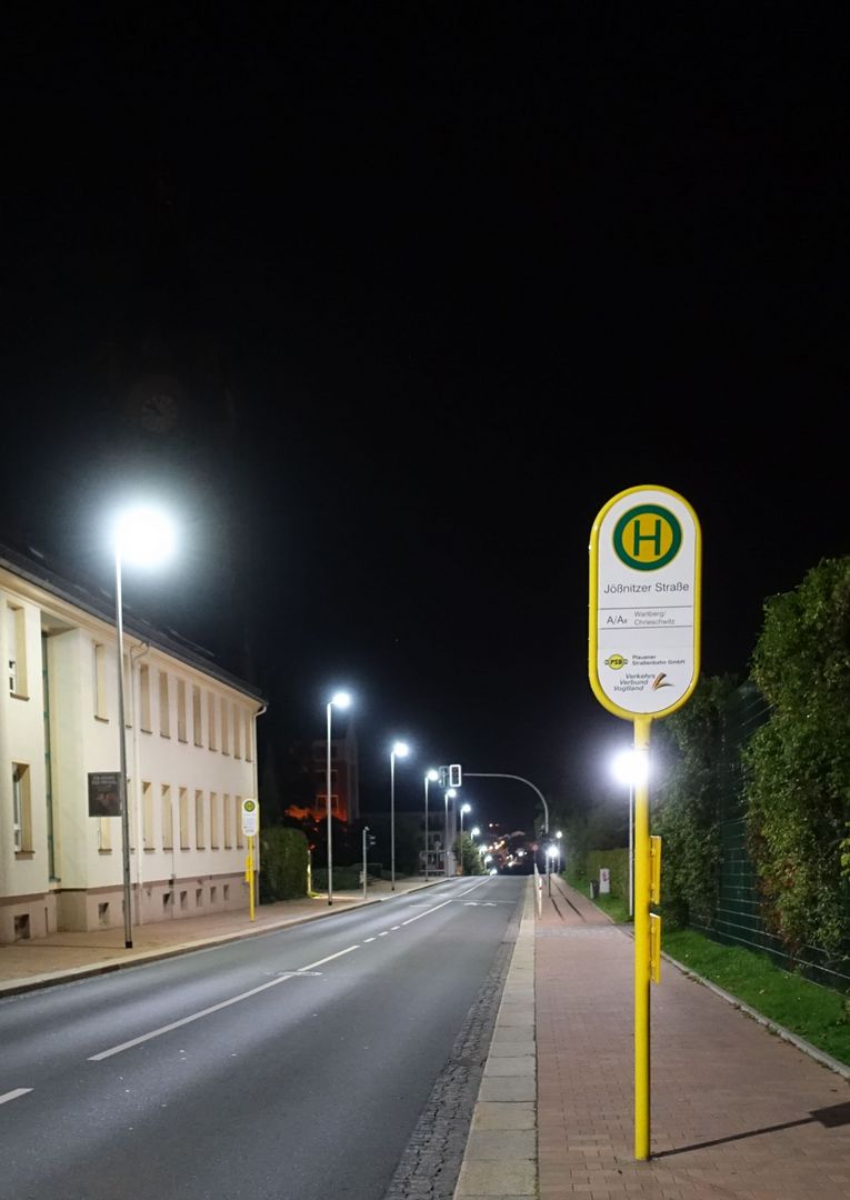 Eine menschenleere Straße in Plauen, die nachts hell erleuchtet ist