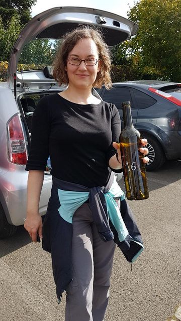Eine Frau zeigt eine leere Weinflasche vor