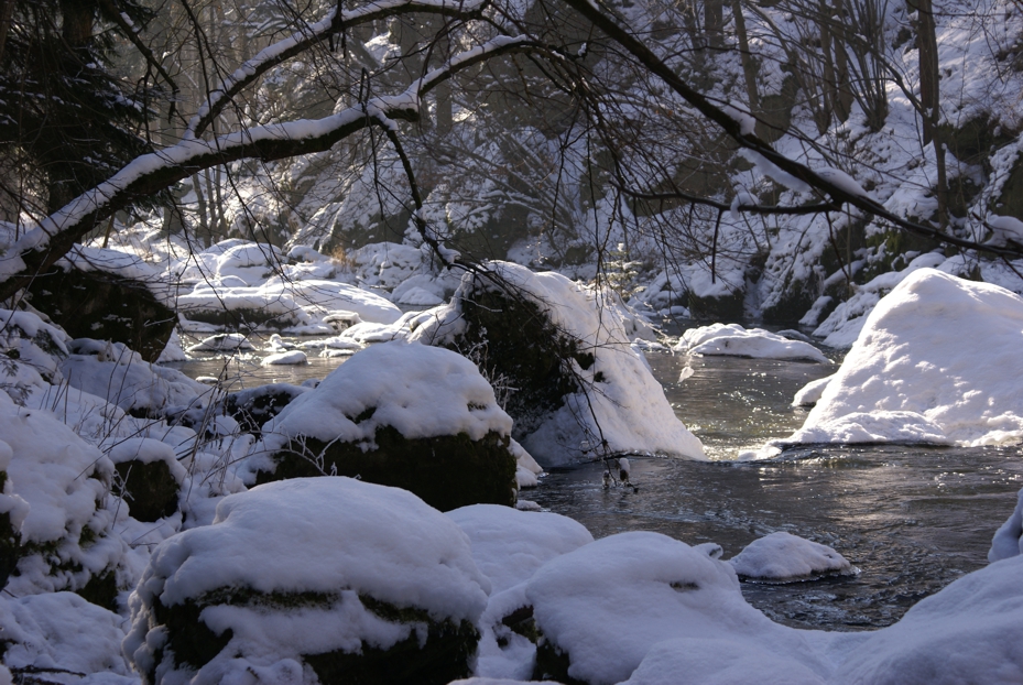 Bach in einer Schlucht mit schneebedeckten Gesteinsblöcken