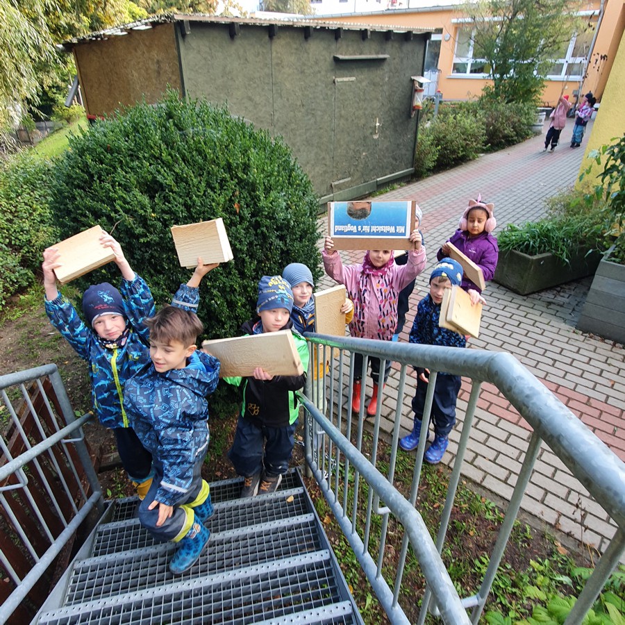 Kinder tragen Holzbretter eine Treppe hinauf
